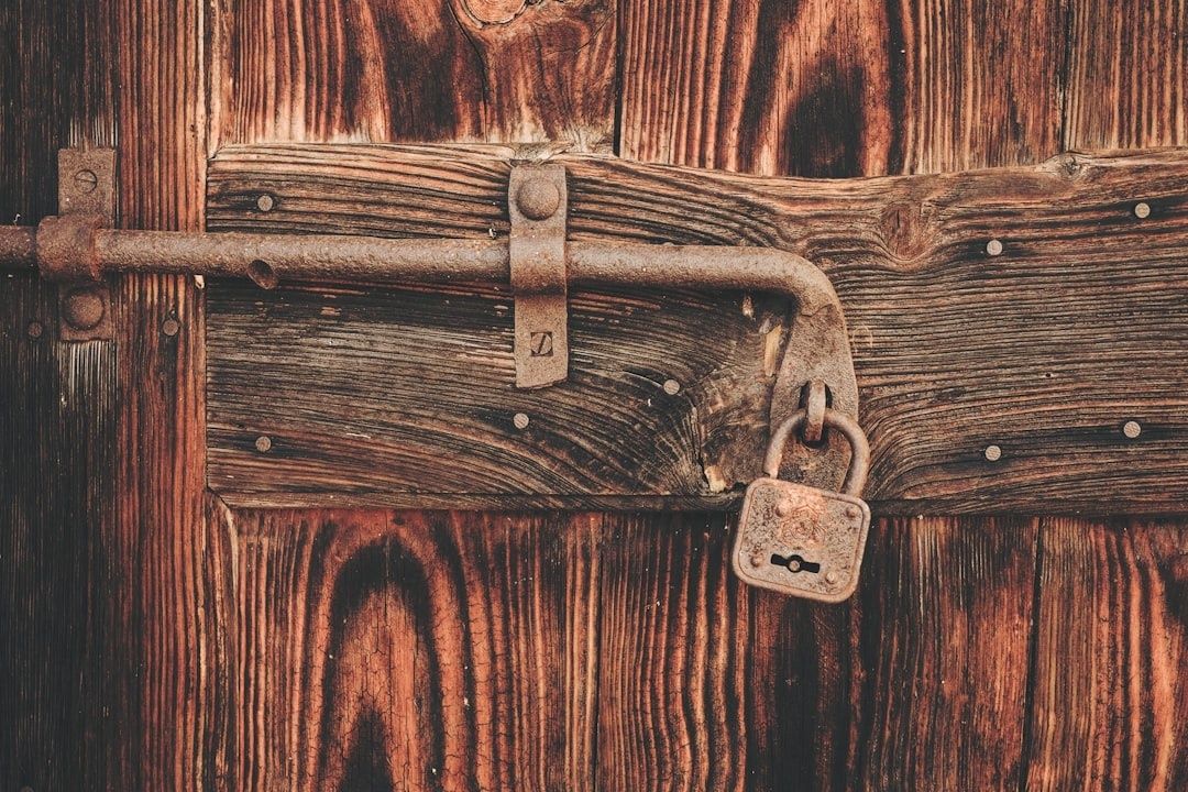 Ancienne porte en bois verrouillée par une barre et un cadenas rouillé