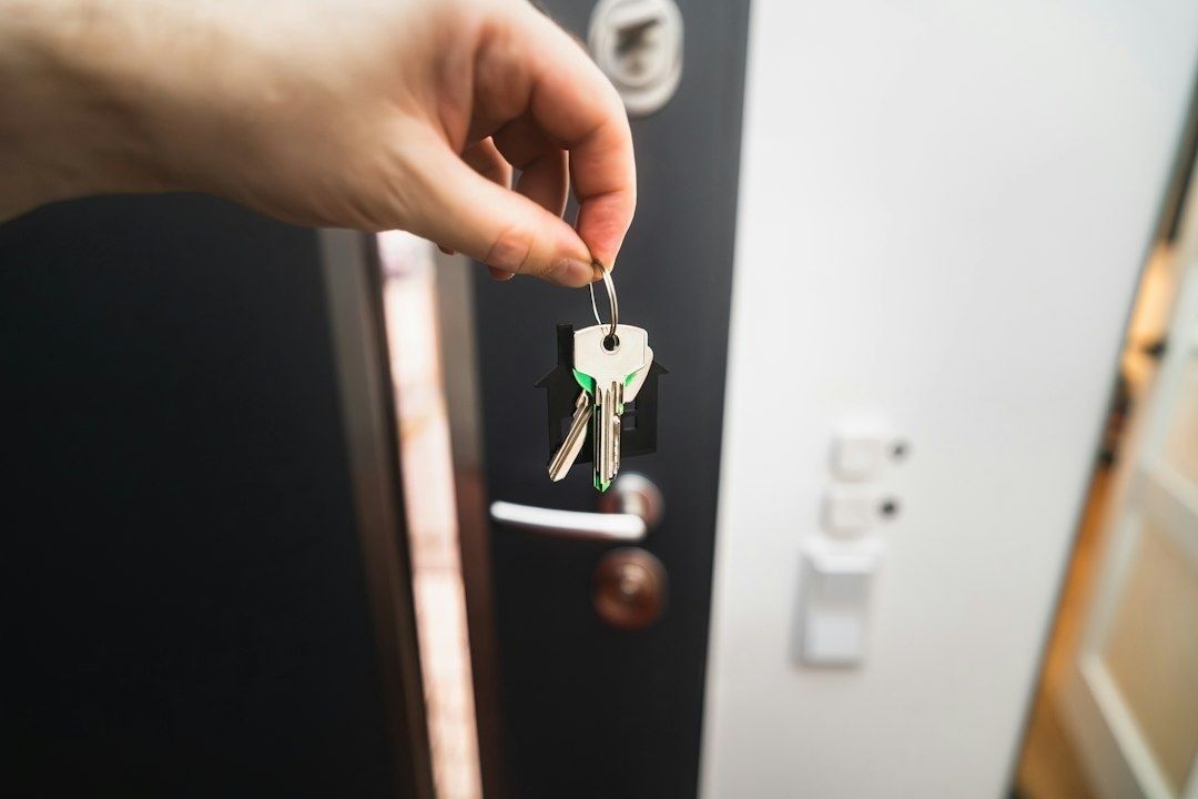 Main tenant un trousseau de clés devant une porte d