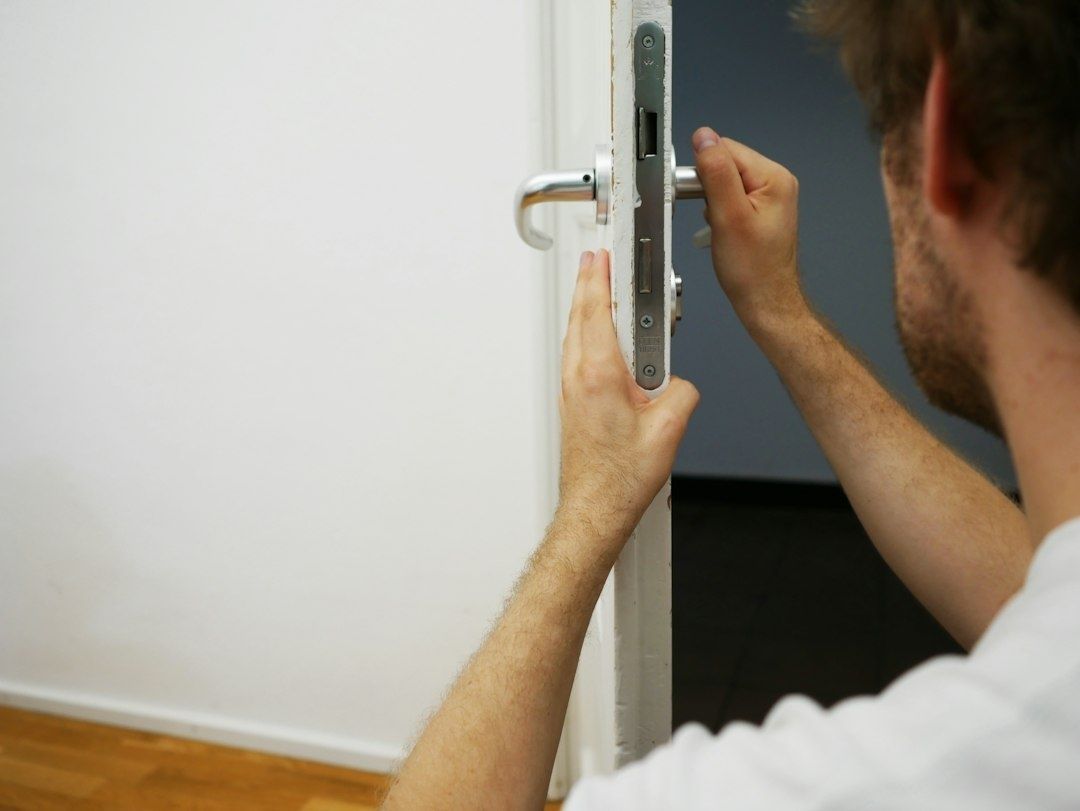 Homme manipulant la serrure d’une porte blanche ouverte